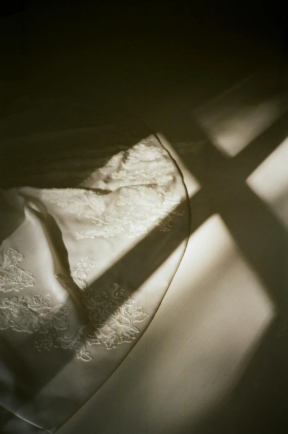 Lace on a wedding dress, crossed by window light and shadow