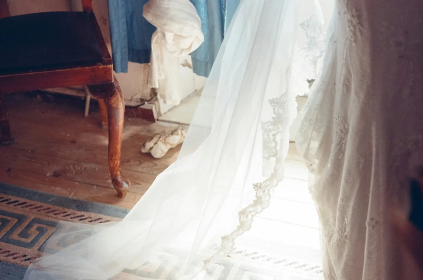 A veil and wedding dress catching the light by a window