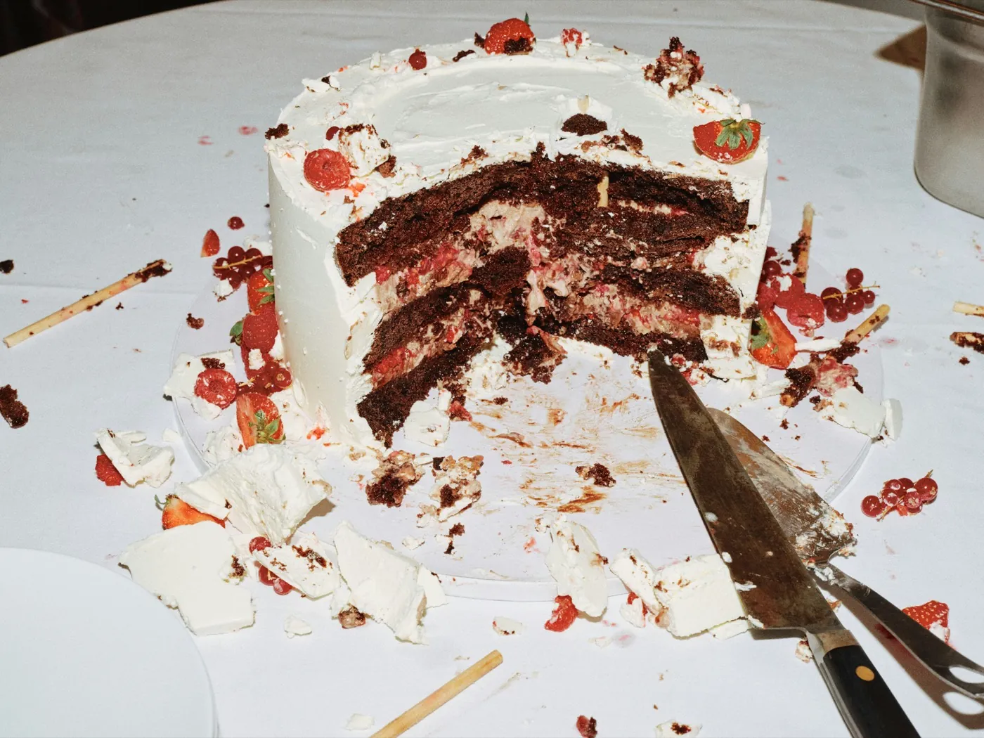 A generously cut chocolate wedding cake with berries, mid-celebration