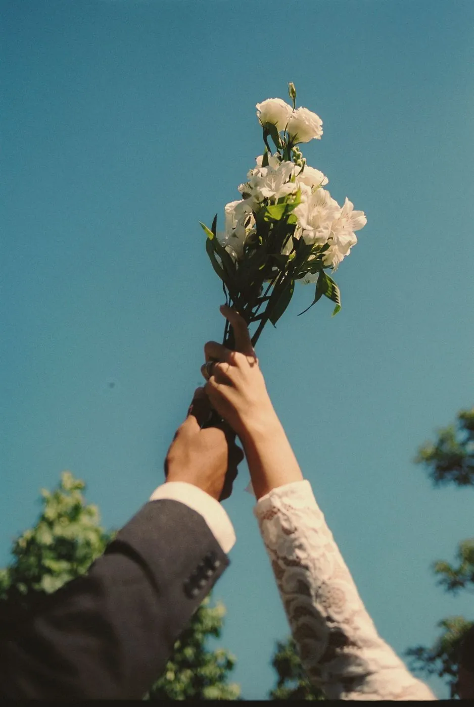 Two hands raising a white bouquet to the sky
